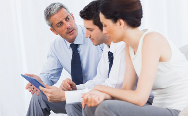 Business people talking about files on sofa at office